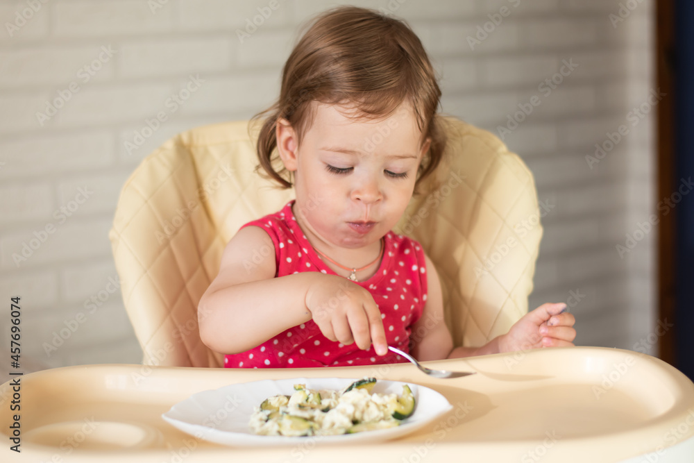 A small European child will eat a spoonful of vegetable and egg lasagna on their own. The baby chews healthy and wholesome food. A small European child will eat a spoonful of vegetable and egg lasagna on their own. The baby chews healthy and wholesome food.