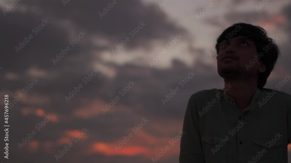 Silhouette of a man standing in front of the sunset and looking at the sky Silhouette of a man standing in front of the sunset and looking at the sky