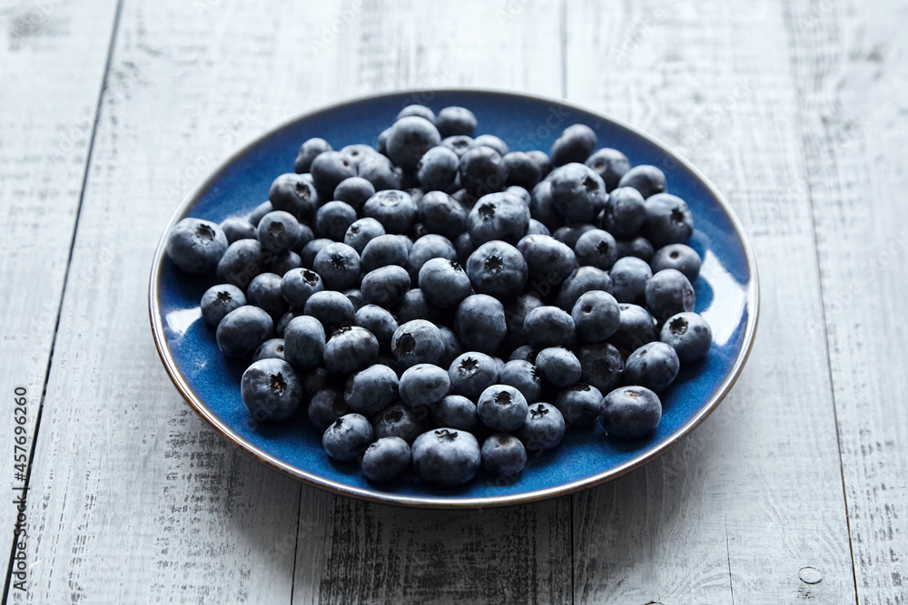 Blueberries on blue plate on wooden table Blueberries on blue plate on wooden table
