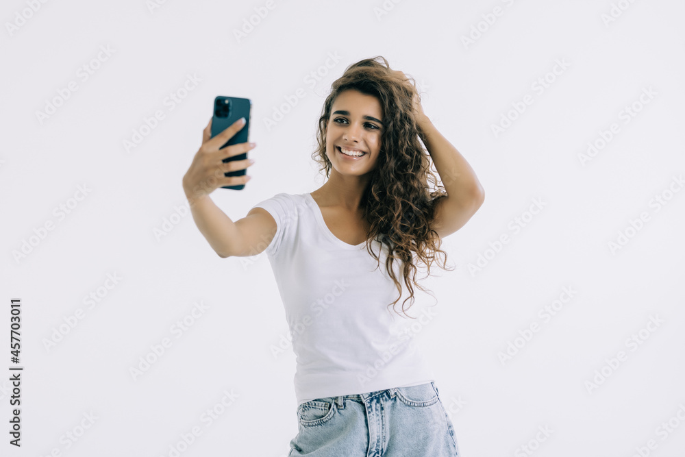 Smiling young woman making selfie photo while waving palm isolated on a white background Smiling young woman making selfie photo while waving palm isolated on a white background