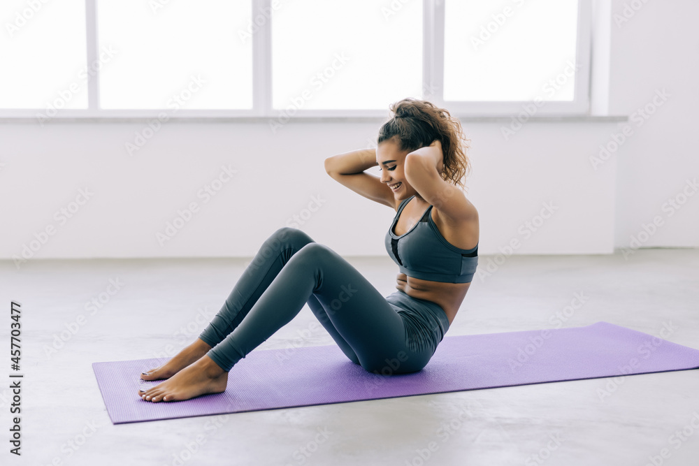 Sporty young woman athlete on yoga mat doing situps in gym. Fitness woman doing abs crunches. Sporty young woman athlete on yoga mat doing situps in gym. Fitness woman doing abs crunches.