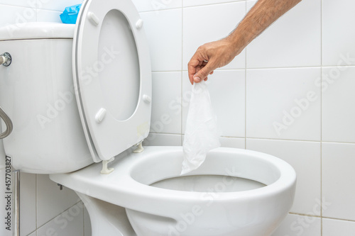 Hand throwing wet wipe into toilet