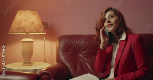 Giovane ragazza italiana parla al telefono seduta sul divano di casa photo