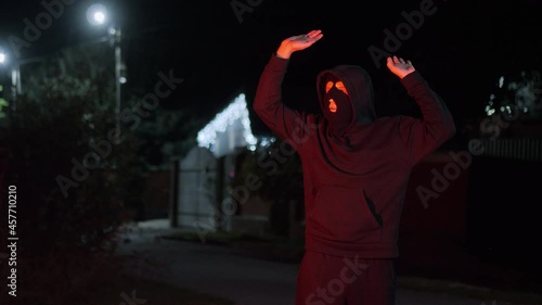 Thief in a mask carries a stolen TV late at night, is caught by the police with flashing lights, funny raises his hands up and drops the TV, concept of security and violation of the law