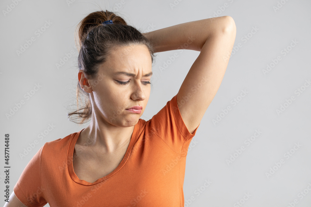 Young woman smelling her armpits Young woman smelling her armpits