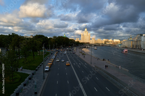 Amazing architecture view of Stalin skyscraper and river Moscow shore. Dramatic view of city landscape embankment with highway, traffic, bridge, cars and park in downtown of Russia capital center.