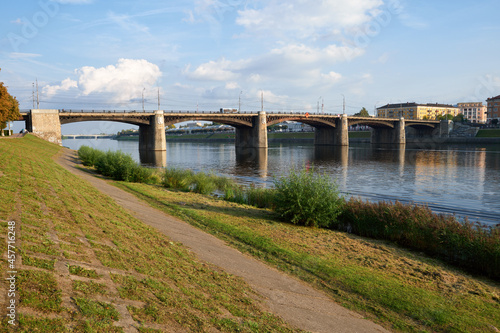 Beautiful city Tver landscape view of stone bridge on river Volga embankment at sunny autumn day with tree,  clear blue sky and old russian buildings. Small city architecture concept. Tver, Russia.