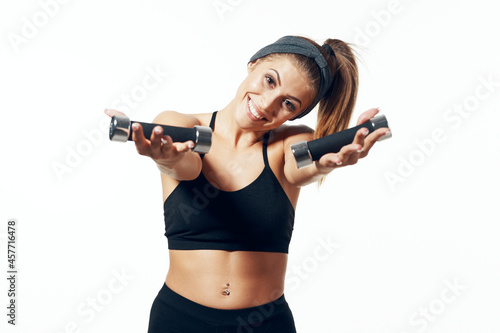 Strong woman wearing sportswear with dumbbells in hands on white background