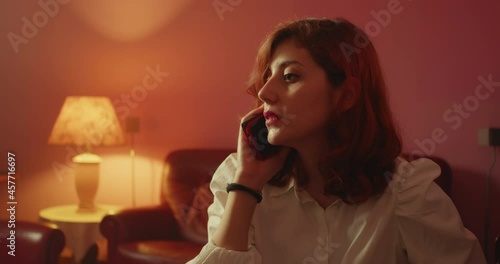 Giovane ragazza italiana parla al telefono seduta sul divano di casa photo