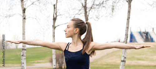 Young woman goes in for sports in the park near the house. Stretching exercises. Photo series