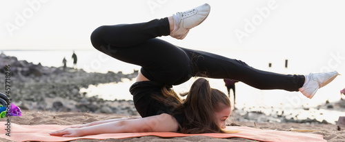 Girl gymnast trains on the beach by the sea. Photo series