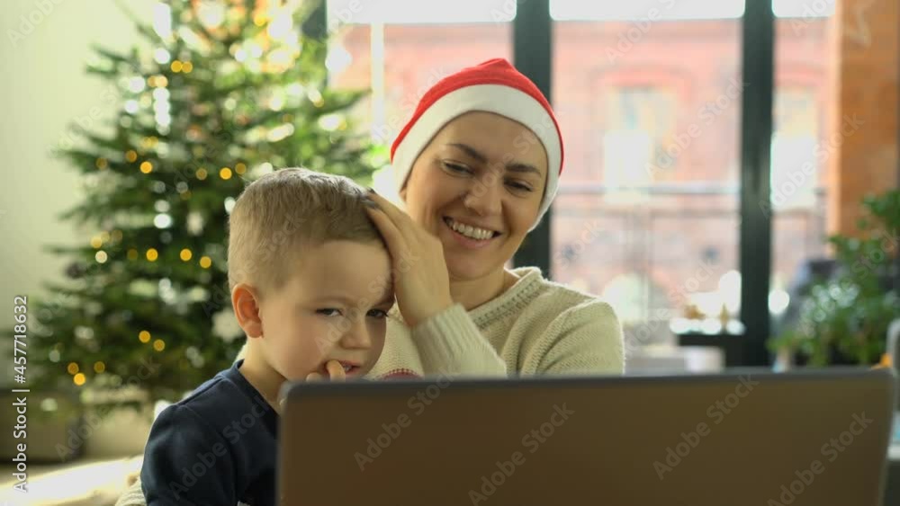 Smiling mother and son using laptop for video call friends and parents on Christmas Smiling mother and son using laptop for video call friends and parents on Christmas
