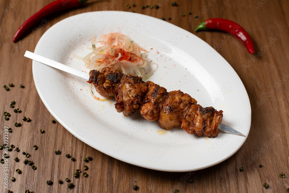 meat kebab on a stick in a white plate with onions meat kebab on a stick in a white plate with onions