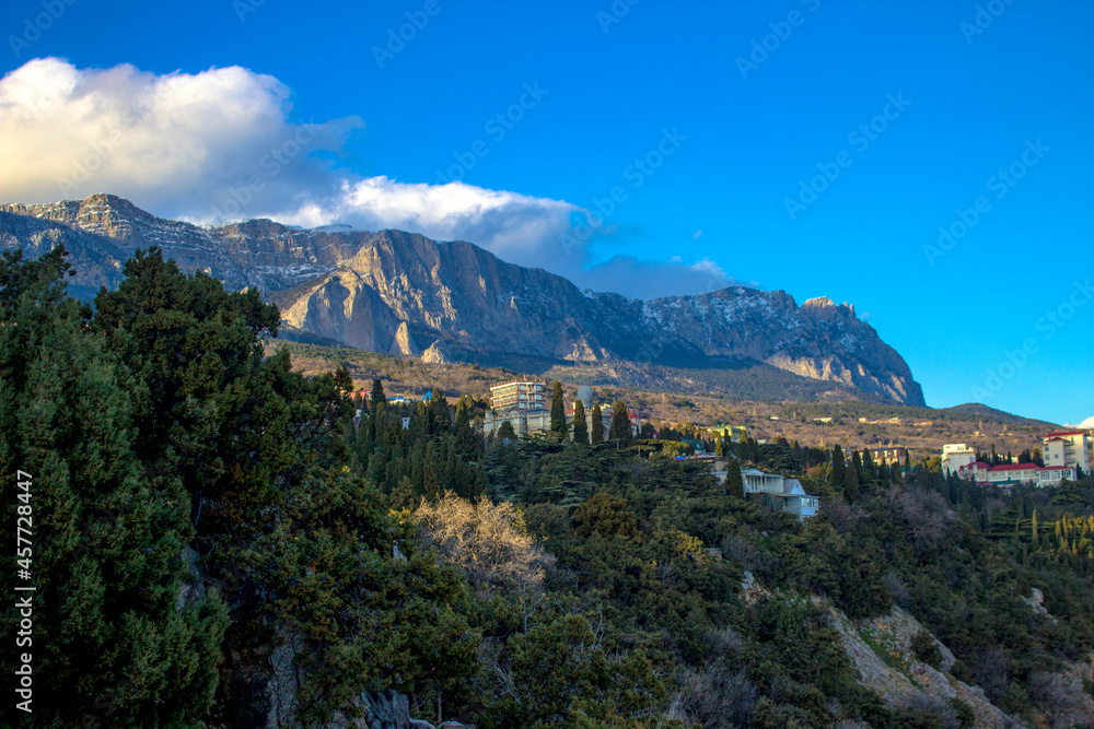 The city of Simeiz at the foot of the mountains with blue skies and overhanging clouds.