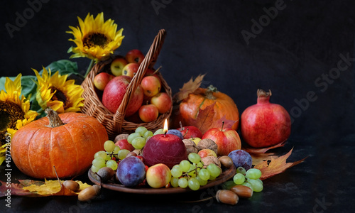Wiccan altar for Mabon sabbat. Candle, seasonal fruits, pumpkins, flowers, nuts on black background. pagan, Wiccan traditions. Witchcraft, esoteric spiritual ritual. 