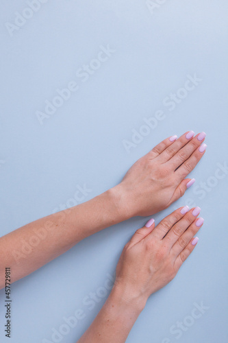 Stylish trendy female manicure. Beautiful young woman's hands on blue background.