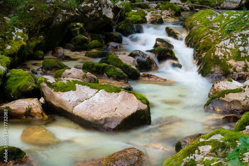 Blurred image of beautiful stream of water flowing over mossy rocks