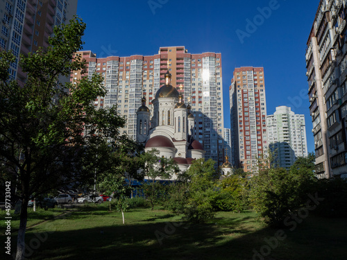 Orthodox Church with gold domes next to high multi-storey buldings. Dormitory area of Kyiv  Ukraine