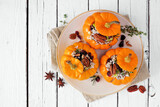 Stuffed mini pumpkins with rice, cranberries, cabbage and nuts. Autumn food concept. Top view on plate over a white wood background.