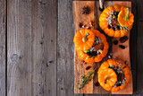 Stuffed mini pumpkins with rice, cranberries, cabbage and nuts. Fall food concept. Above view on platter over a rustic wood background. Copy space.