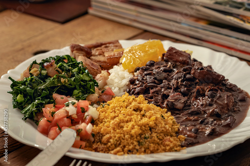 Prato feito de feijoada e acompanhamentos, arroz, vinagrete, couve, panceta e um pedaço de laranja