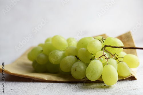 Bunch of grapes in a small kraft paper bag. Stone background, copy space.