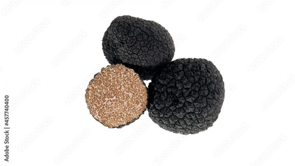 Top view of two whole and one halved black truffle mushrooms rotating. Isolated on white background. Top view of two whole and one halved black truffle mushrooms rotating. Isolated on white background.