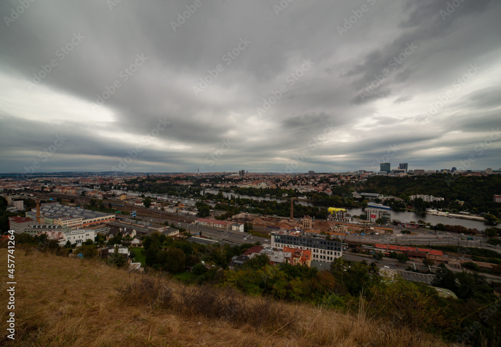 Une vue panoramique de la ville de Prague. Une vue sur le centre-ville de Prague avec tous les monuments historiques, le fleuve ainsi que la gare Smichov. Le ciel est gris et menaçant.