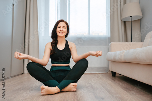 Young woman is sitting on the floor in a room doing yoga stretching.Concept healthy lifestyle.