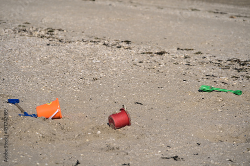 Closeup view of colorful children plastic toys left or forgotten at Sandymount Beach after messy sea activities during lowest tide, Dublin, Ireland. Conceptual. Copy space. Soft and selective focus photo