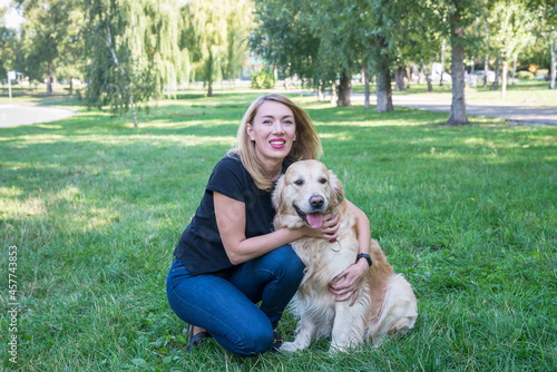 Young blond woman hugs her dog.