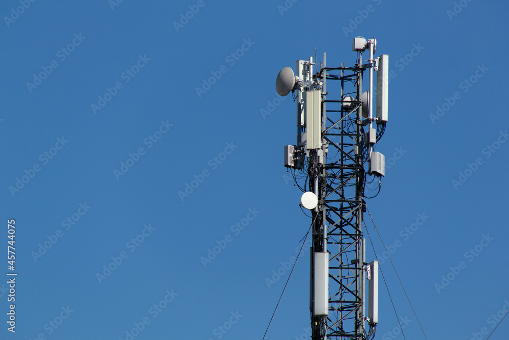 Mobile cell phone tower against the background of a blue sky and white cloud. Telecommunication TV tower. Cellular antenna. Wi-fi transmitter and receiver module. Mobile cell phone tower against the background of a blue sky and white cloud. Telecommunication TV tower. Cellular antenna. Wi-fi transmitter and receiver module.