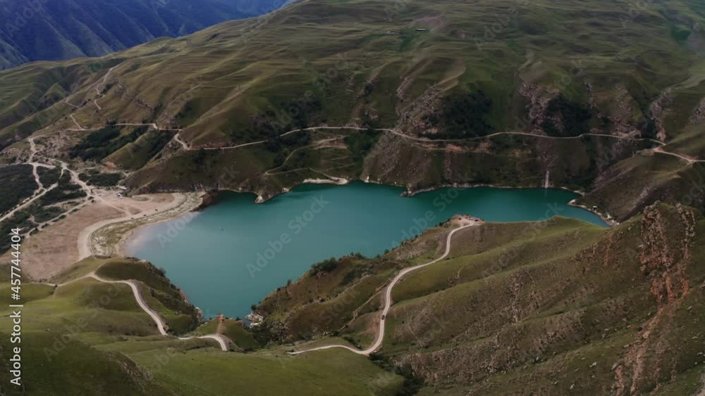 A view of clear mountain lake of irregular shape located between green hills A view of clear mountain lake of irregular shape located between green hills