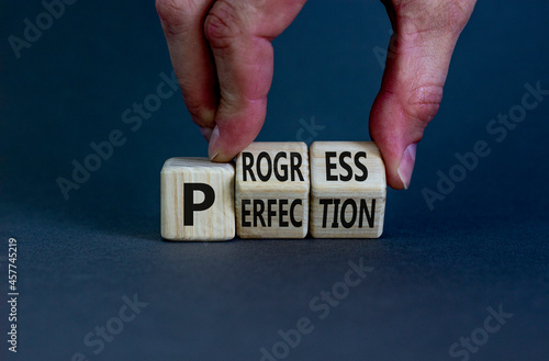 Progress or perfection symbol. Businessman turns cubes and changes the concept word 'perfection' to 'progress' on a beautiful grey background. Copy space. Business, progress or perfection concept.