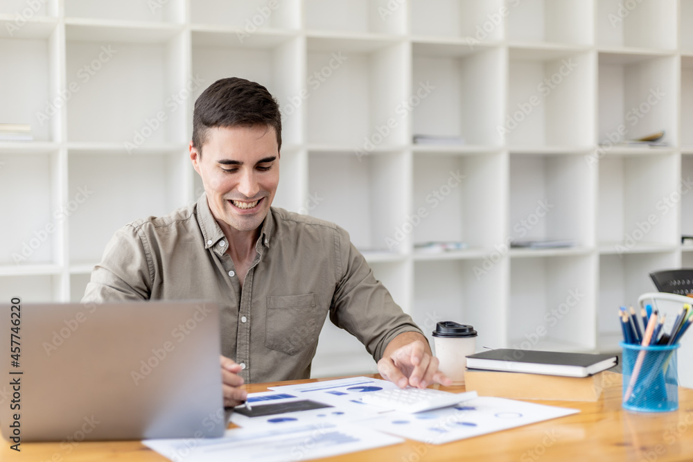 Young businessman sitting and checking financial documents displayed in chart format, young businessman who founded a startup company, managing a new business to grow by leaps and bounds. Young businessman sitting and checking financial documents displayed in chart format, young businessman who founded a startup company, managing a new business to grow by leaps and bounds.