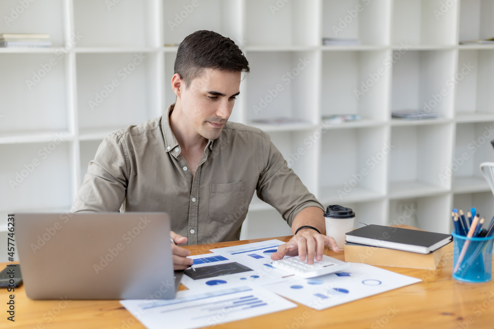 Young businessman sitting and checking financial documents displayed in chart format, young businessman who founded a startup company, managing a new business to grow by leaps and bounds. Young businessman sitting and checking financial documents displayed in chart format, young businessman who founded a startup company, managing a new business to grow by leaps and bounds.