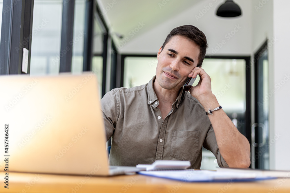 Man talking on the phone in the office, He is a businessman executive of a startup company founded with partners, He is a young and energetic executive and the company's earnings continue to grow. Man talking on the phone in the office, He is a businessman executive of a startup company founded with partners, He is a young and energetic executive and the company's earnings continue to grow.
