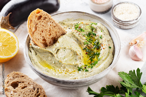 Baba ghanoush, babaganoush or eggplant hummus on the bowl with bread and all ingredients, close up photo