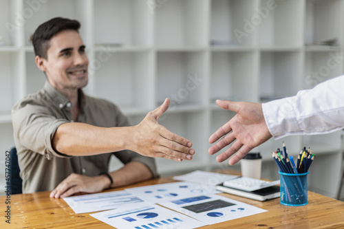 A young businessman is shaking hands with a business partner after a discussion. Two businessmen shaking hands. A handshake is a gesture of respect or congratulation. Business etiquette concept.