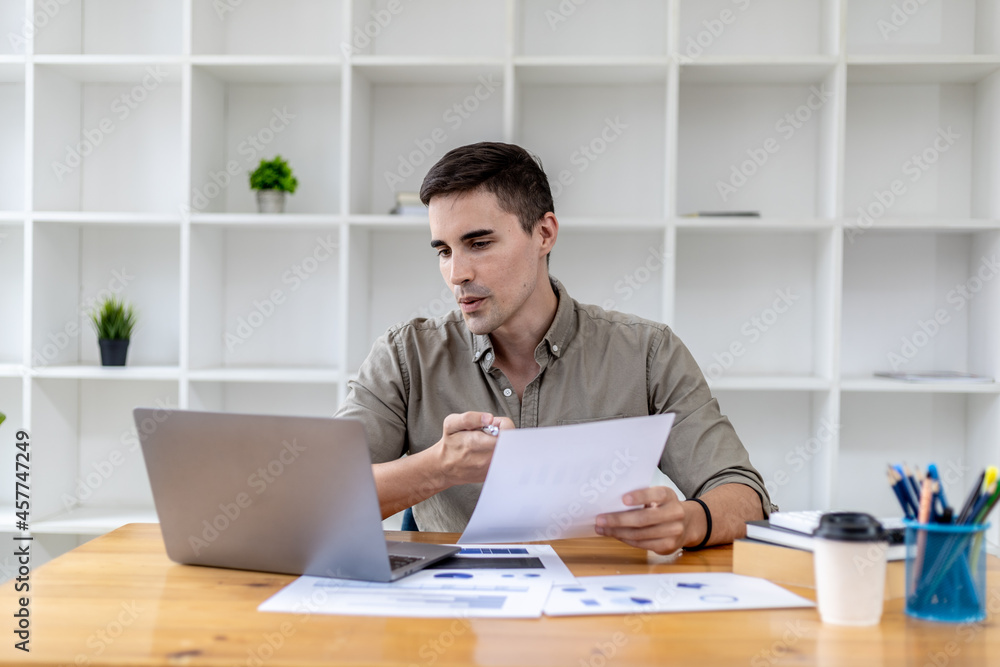 A young businessman is discussing a laptop video conference with a business partner who founded a startup company together, they have a company finance meeting to fix and plan financial arrangements. A young businessman is discussing a laptop video conference with a business partner who founded a startup company together, they have a company finance meeting to fix and plan financial arrangements.