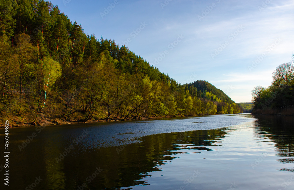 Autumn in the river valley: contagious yellow foliage, winding streams and a choppy sky. Wooded mountains along the banks of the dark river.