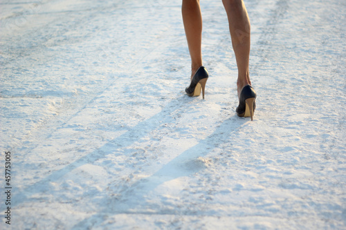 cropped photo of female legs in shoes on snow. selective focus