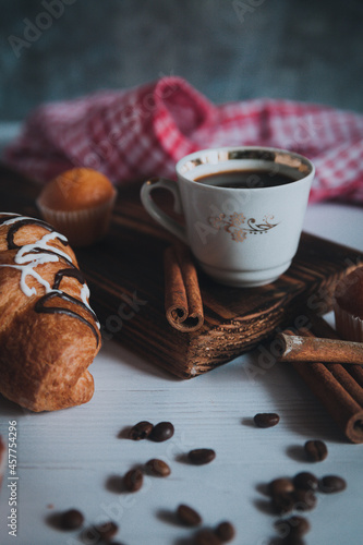 A cup of aromatic black coffee, grains of different varieties on the table. Morning espresso or Americano coffee for breakfast in a beautiful cup. Still life. Cinnamon sticks.