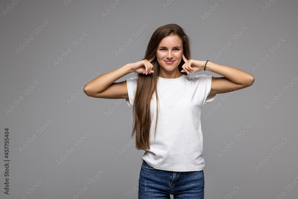 Too loud sound. Beautiful young woman covering ears with hands and keeping eyes closed while standing against grey background Too loud sound. Beautiful young woman covering ears with hands and keeping eyes closed while standing against grey background