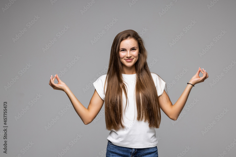 Happy smiling young woman gesturing with hands and showing balance isolated on gray background Happy smiling young woman gesturing with hands and showing balance isolated on gray background