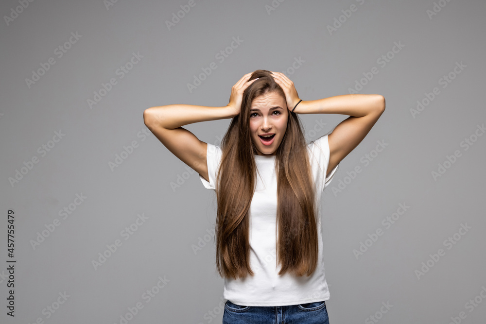Fototapeta premium Surprised shocked young woman standing with opened mouth isolated over grey background