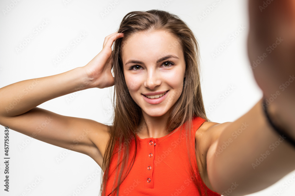 Portrait of a happy young woman making funny face while taking pictures of herself over white background Portrait of a happy young woman making funny face while taking pictures of herself over white background