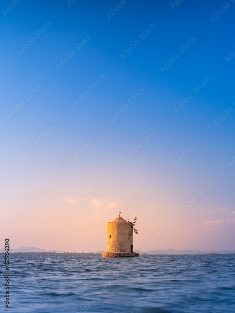 old windmill at sea under blue sky in sunset time with copy space in Orbetello in Tuscany in Italy