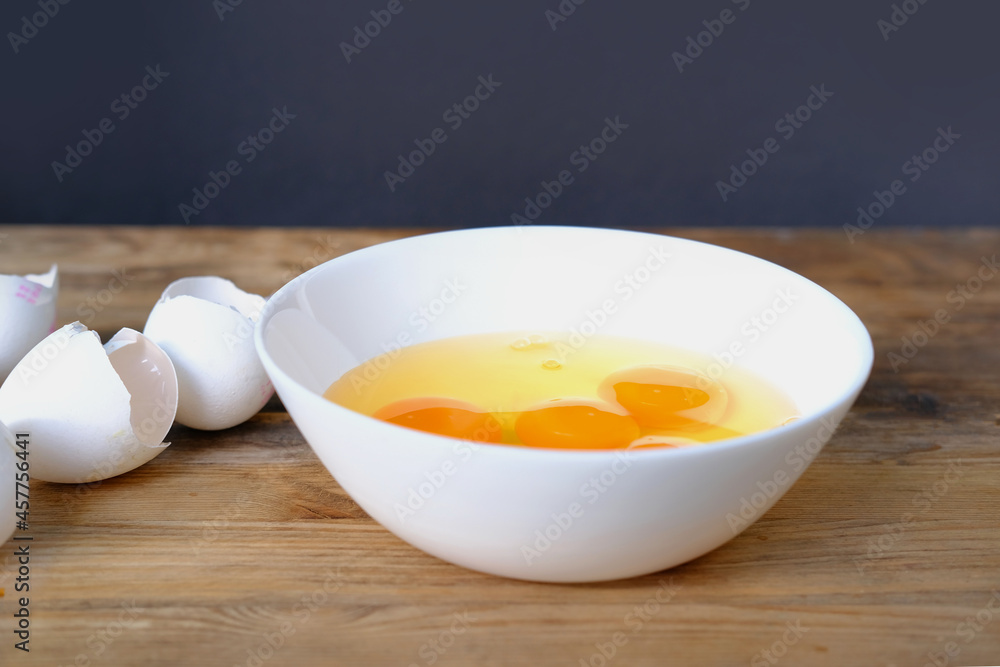raw chicken eggs in a white cup on the table, broken shells, the concept of cooking scrambled eggs, omelet, home cooking raw chicken eggs in a white cup on the table, broken shells, the concept of cooking scrambled eggs, omelet, home cooking