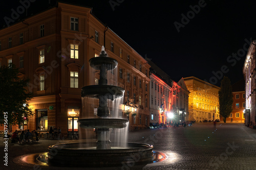 Ljubljana Fountain on Novi trg square at night with illuminated buildings